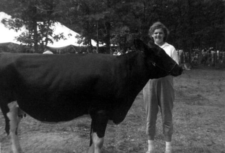 Catherine Longley behind head of large black holstein with white patches on legs