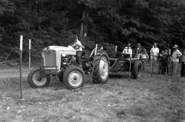 Melvin backing manure spreader in staked course toward group of people behind