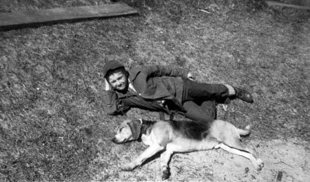 boy (awake) and dog (sleeping) lying on ground